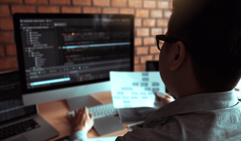 Rear view of the software developer is working on a computer keyboard